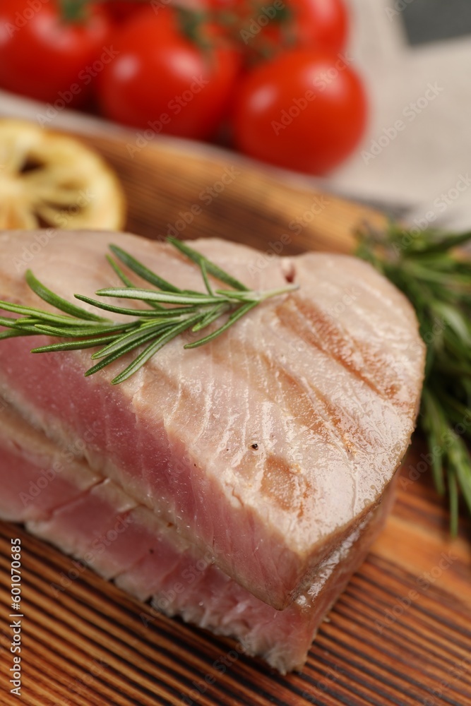 Pieces of delicious tuna steak with rosemary on wooden board, closeup Pieces of delicious tuna steak with rosemary on wooden board, closeup