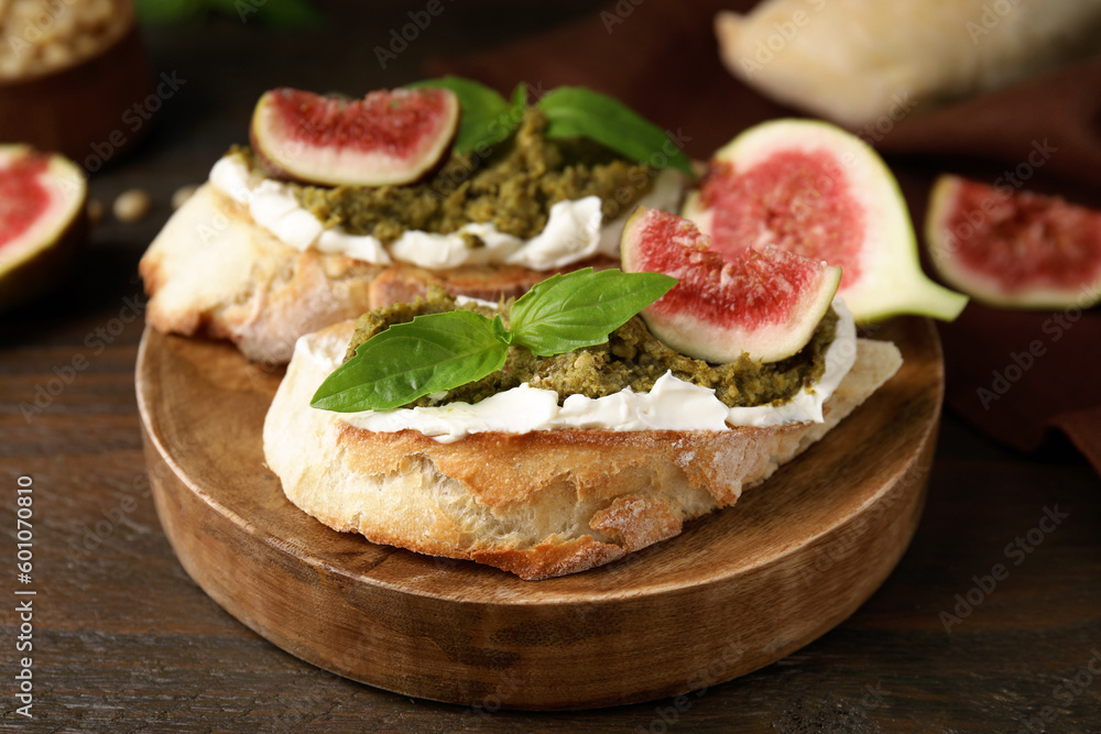 Tasty bruschettas with cream cheese, pesto sauce, figs and fresh basil served on wooden table, closeup Tasty bruschettas with cream cheese, pesto sauce, figs and fresh basil served on wooden table, closeup