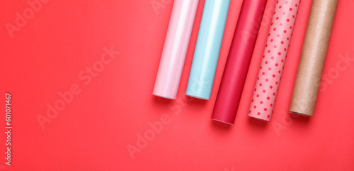 Rolls of colorful wrapping papers on red background  flat lay. Space for text