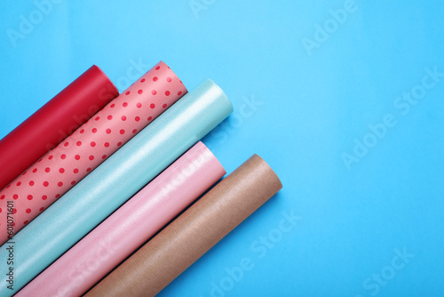 Rolls of wrapping papers on light blue background, flat lay. Space for text