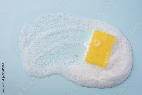 Cleaning sponge and a soapy foam on a blue background. Cleaning concept, cleaning service. Banner. Flat lay, top view