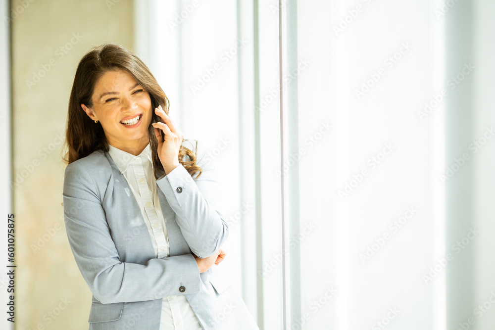 Young woman with mobile phone by the window Young woman with mobile phone by the window
