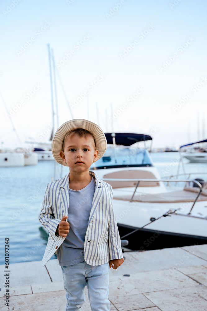 Cute stylish boy posing near yacht in marina Cute stylish boy posing near yacht in marina