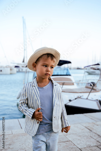 Cute stylish boy posing near yacht in marina