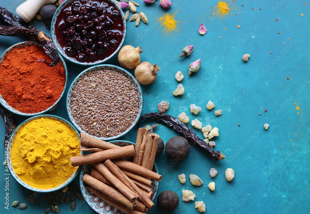 Spices and herbs on turquoise background with copy space. Food and cuisine ingredients. Colorful spices in bowls on blue background, top view
