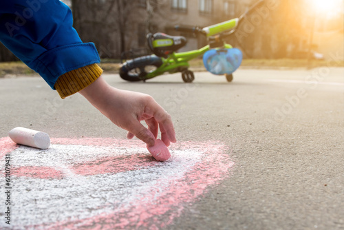 a child draws with chalk on the asphalt on the background of a bicycle