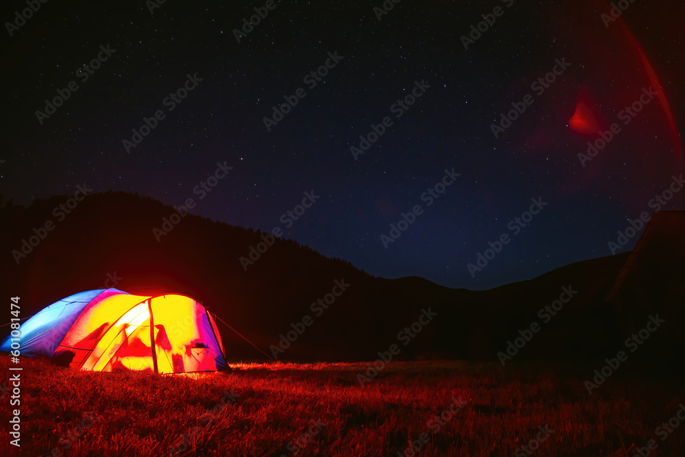 The tourist tent is illuminated by light. Starry sky. Tourism and active recreation. Overnight, camping in the Carpathian mountains, Ukraine. Copy space. - obrazy, fototapety, plakaty 