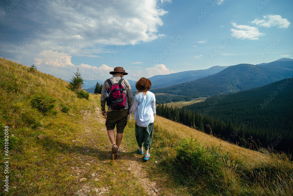 Man and woman move on their hiking trip, the mountain trail. Carpathians mountains, hiker couple enjoying vacation. Sunny day. Travel and tourism. Ukraine