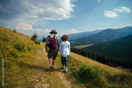 Man and woman move on their hiking trip, the mountain trail. Carpathians mountains, hiker couple enjoying vacation. Sunny day. Travel and tourism. Ukraine © Sergey