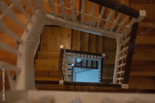 The view of the cat in the perspective of a wooden staircase, the view inside the house from top to bottom.