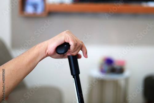 Close up photo of elderly man's hand with walking stick at home