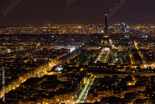 Aerial view of Paris at night with a dark Eiffel Tower and La DÃ©fense business district in the background, as seen from the Tour Montparnasse, France