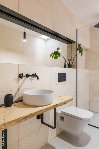 Light style bathroom with a toilet bowl  big mirrors and a sink and a glass shower cabin. The concept of a stylish but simple renovation in a new building