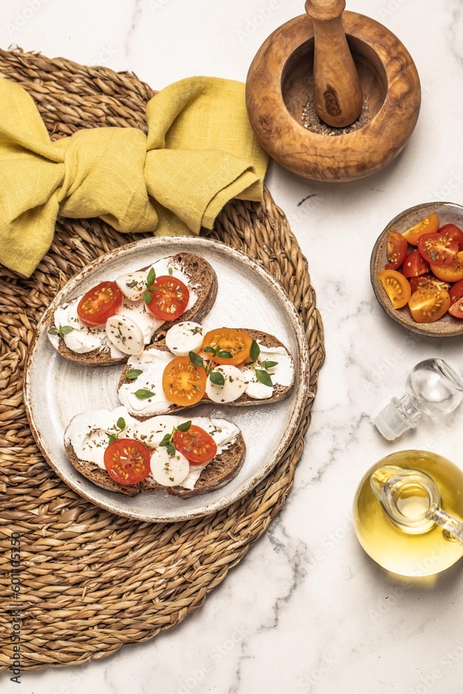 Bruschetta with mozzarella, tomatoes and thyme. Olive oil. Wooden mortar. Light background. Summer snack.