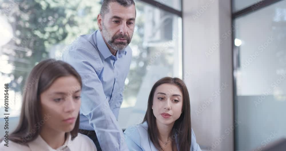 Young bussiness colleagues working in an office. Senior supervisor standing and giving advice. Successful team solving a problem. Young bussiness colleagues working in an office. Senior supervisor standing and giving advice. Successful team solving a problem.