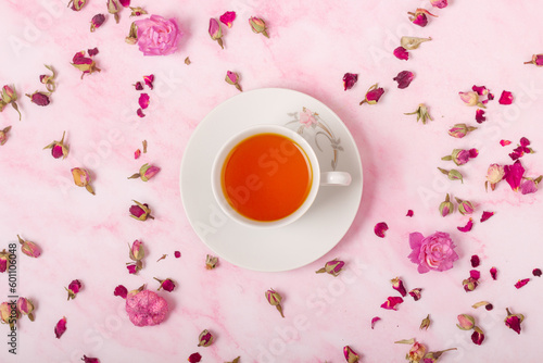 Cup of tea on pink background with flowers. Top view. closeup