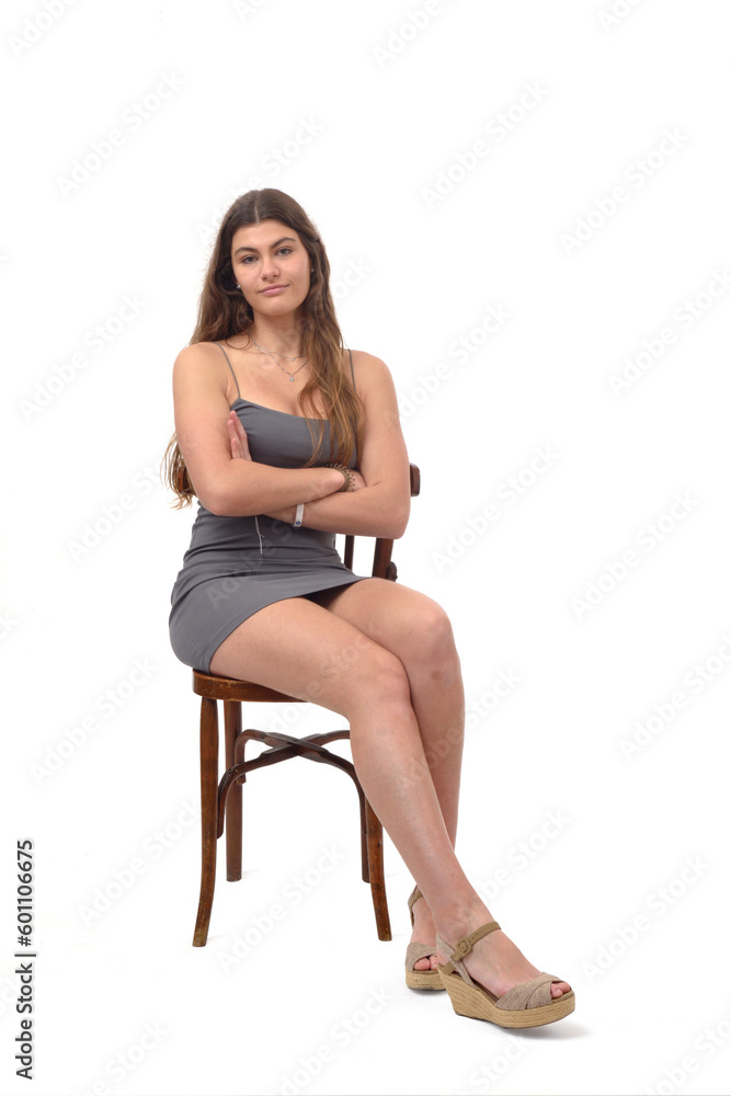 front view of young girl sitting on chair looking at camera and arms crossed on white background front view of young girl sitting on chair looking at camera and arms crossed on white background
