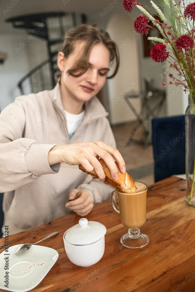 The girl drinks coffee and eats a croissant. The girl drinks coffee and eats a croissant.