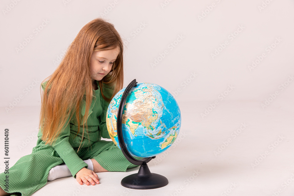 The girl looks at the globe with interest and finds on it unfamiliar countries for herself. little girl dreams of traveling The girl looks at the globe with interest and finds on it unfamiliar countries for herself. little girl dreams of traveling