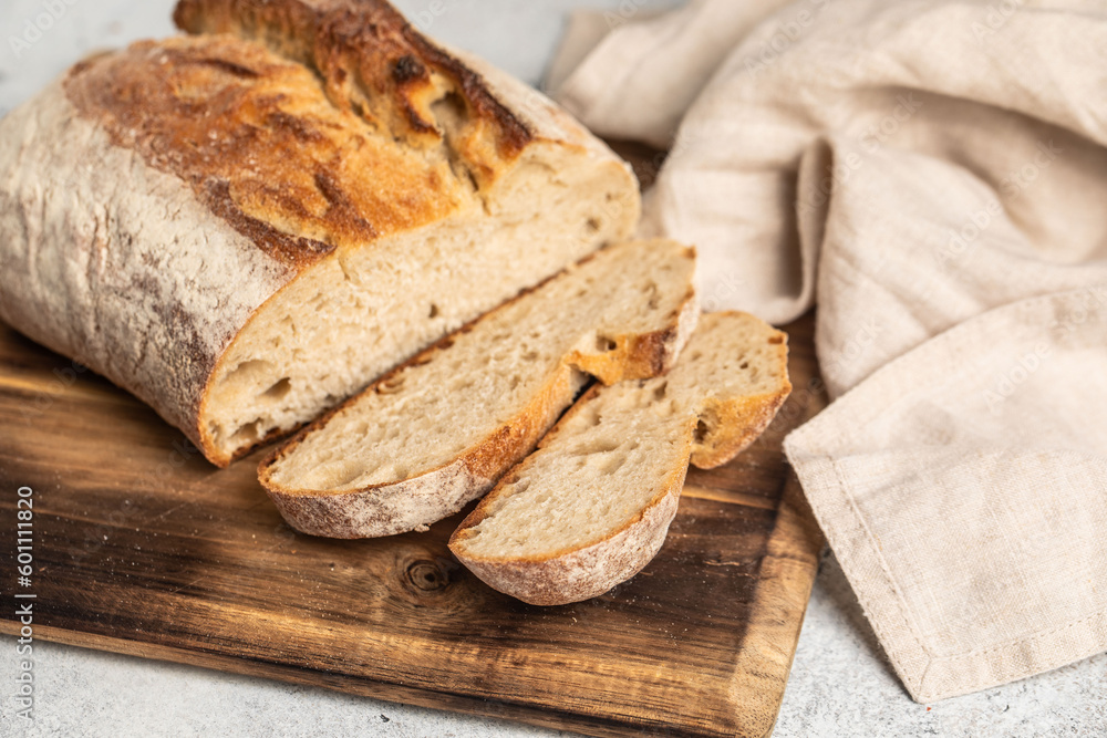 Fresh bread with a crispy crust on a wooden board. Sliced ​​bread. Napkin.