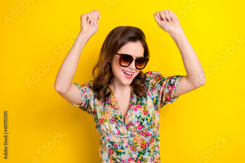 Portrait of excited carefree lady raise hands enjoy music dancing partying isolated on yellow color background