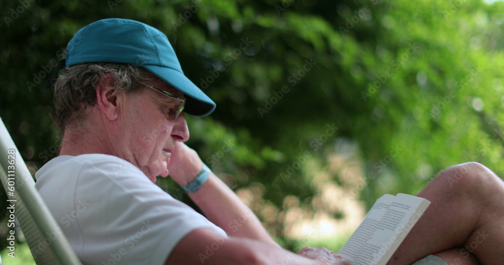Candid senior man reading book in the daylight. Casual retired older man reading book Candid senior man reading book in the daylight. Casual retired older man reading book