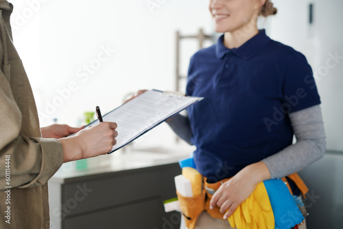 Fotografia Close-up of housewife signing a contract with cleaning service worker to hire pr