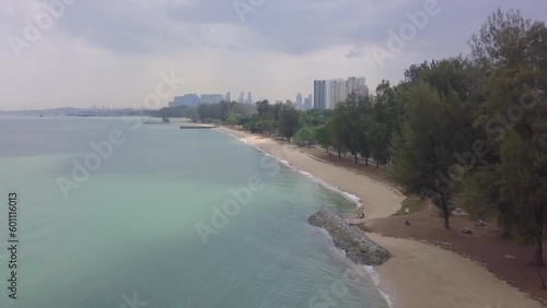 Aerial drone view of East Coast Park Beach revealing the urban buildings in the background - Singapore 2021