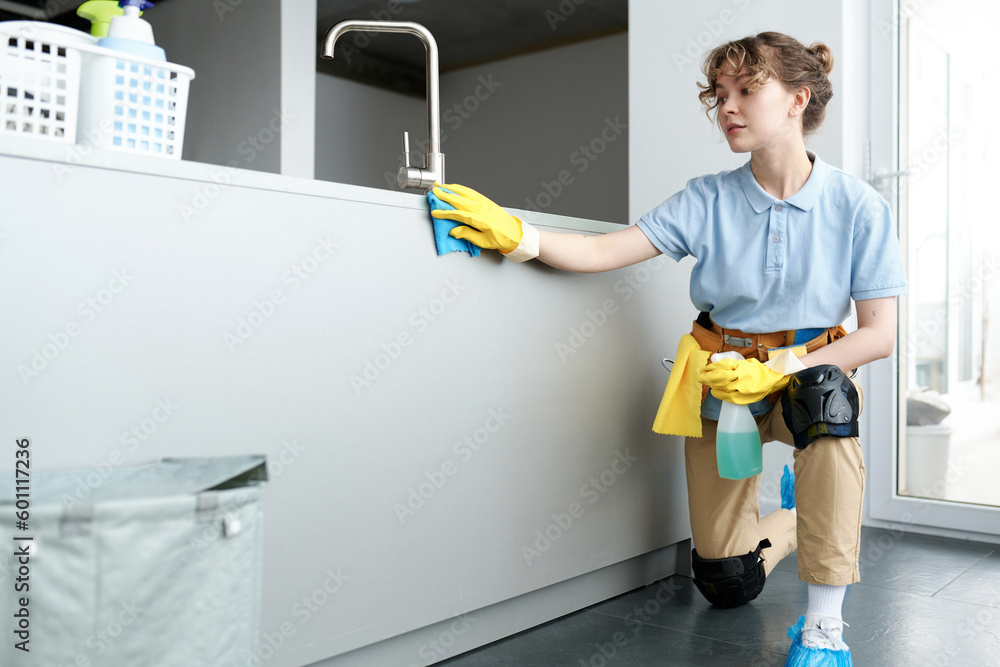 Professional cleaning service worker in protective gloves wiping dust in the kitchen during housework Professional cleaning service worker in protective gloves wiping dust in the kitchen during housework