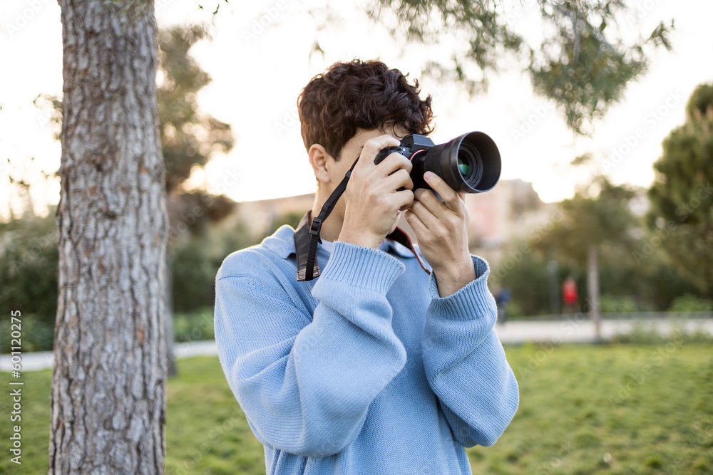 Young man shooting photos near tree on green grass Young man shooting photos near tree on green grass