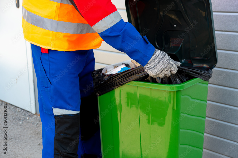 Janitor takes garbage out of trash container outdoors Janitor takes garbage out of trash container outdoors