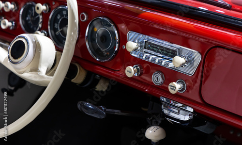 Dashboard of a stylish red classic car. The excellent restoration of the vehicle and whitesteering wheel rim are visible