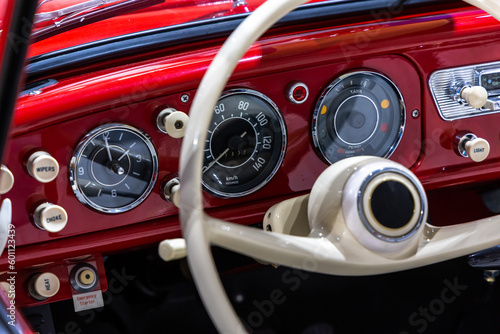 Dashboard of a stylish red classic car. The excellent restoration of the vehicle and whitesteering wheel rim are visible