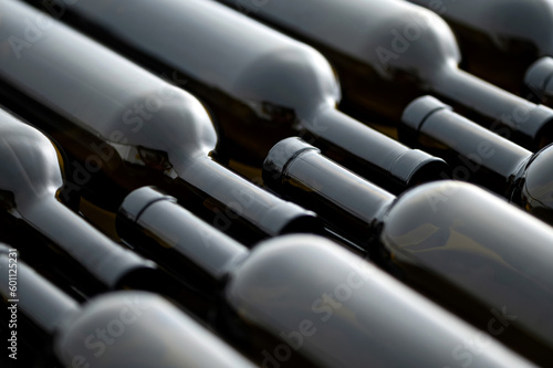 Dark glass wine bottles lie on conveyor belt. Beverage production process. Bottling and packaging of alcoholic beverages. View from above. Close-up. 