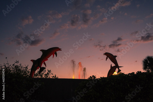 Fototapeta Naklejka Na Ścianę i Meble -  Iconic dolphin statue in Sarasota's Bayfront Park at sunset with dramatic sky.