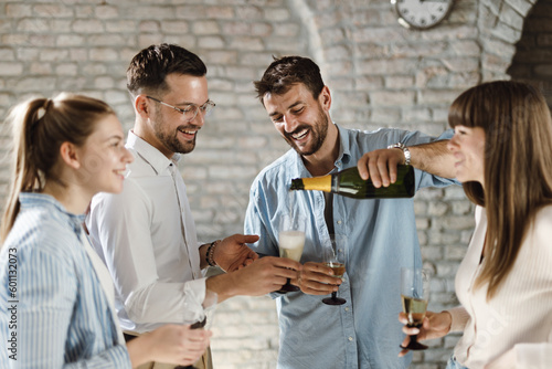 Photography Young business colleagues pouring champagne during a party in the office