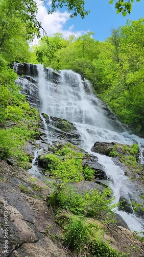 footage of a gorgeous spring landscape with a flowing waterfall over large rocks surrounded by lush green trees and plants at Amicalola Falls State Park in Dawsonville Georgia USA photo