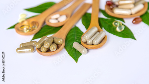 Capsules herb supplements on green leaves background. Selective focus.