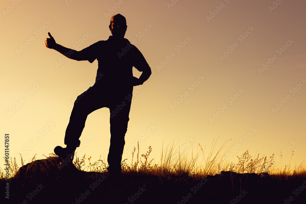 the silhouette of a man against the background of the sunset outside raises a thumbs up the silhouette of a man against the background of the sunset outside raises a thumbs up