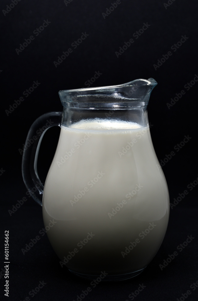 Glass milkman on a black background. A jug of milk. Milk in a vessel. Glass milkman on a black background. A jug of milk. Milk in a vessel.