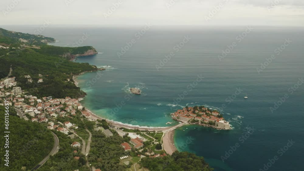 Slow descent on the drone. Landscape, the island of Sveti Stefan and coastal towns. The sea gently washes over the beach. Slow descent on the drone. Landscape, the island of Sveti Stefan and coastal towns. The sea gently washes over the beach.