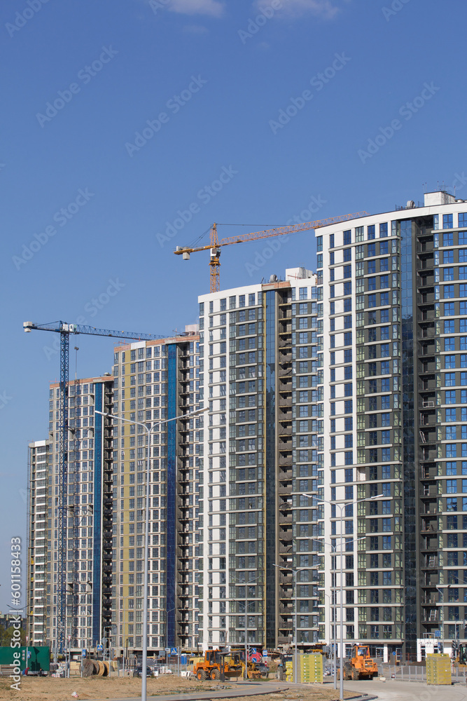 Construction site. Reinforced concrete frames of multi-storey buildings and construction cranes. The final stage of construction. Against the background of the blue sky. Construction site. Reinforced concrete frames of multi-storey buildings and construction cranes. The final stage of construction. Against the background of the blue sky.