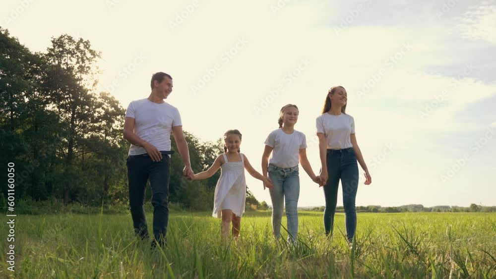 Happy family in park at sunset. mother, father,children girls walk in park at sunset together outdoors on green nature. concept of happy family in nature, parenting, adoption of children, walk in park Happy family in park at sunset. mother, father,children girls walk in park at sunset together outdoors on green nature. concept of happy family in nature, parenting, adoption of children, walk in park
