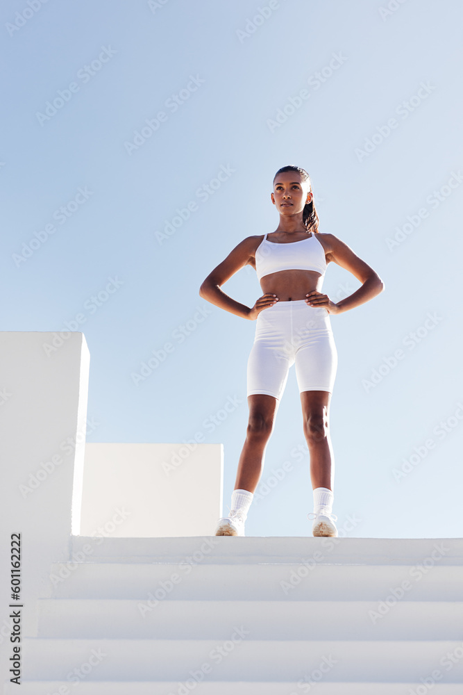 Obraz premium Full length of young slim sportswoman relaxing. Woman with hands on hips standing on the top of stairs.