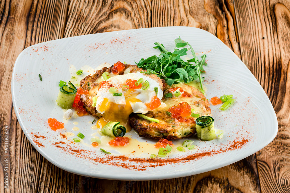 Fried zucchini pancakes with egg, cucumber, red caviar and arugula. Fried zucchini pancakes with egg, cucumber, red caviar and arugula.