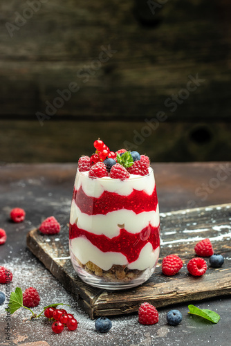 Raspberry dessert cheesecake, trifle, mouse in a glass. Raspberry Greek yogurt granola parfait on a dark background. Restaurant menu, dieting, cookbook recipe