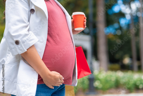 Pregnant woman holding belly and walking outdoors