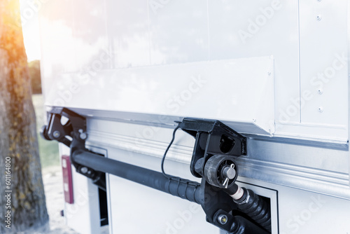 Close-up detail view of modern white delivery truck tail door with hydraulic lift mechanism on city street. Closeup lorry back elevator metal loop equipment photo