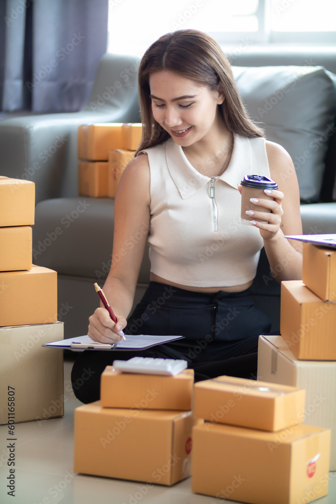 woman checking package of goods from customer online order is alone in her home office as she is an SME entrepreneur and uses her phone and tablet to market online. concept online sales business woman checking package of goods from customer online order is alone in her home office as she is an SME entrepreneur and uses her phone and tablet to market online. concept online sales business