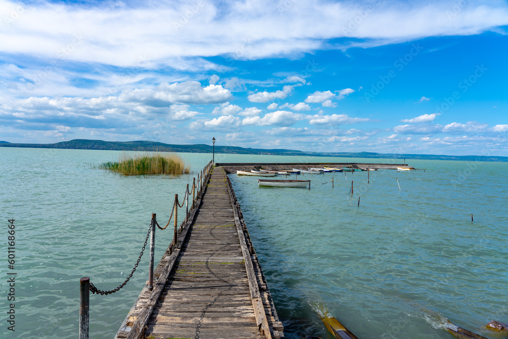 wooden pier in Balatonlelle with colorful boats on lake Balaton blue sky and water